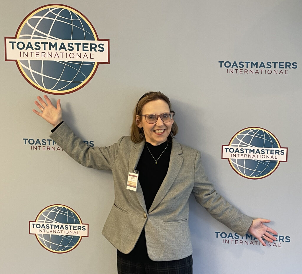 Chris posing in front of a Toastmasters International logo wall.